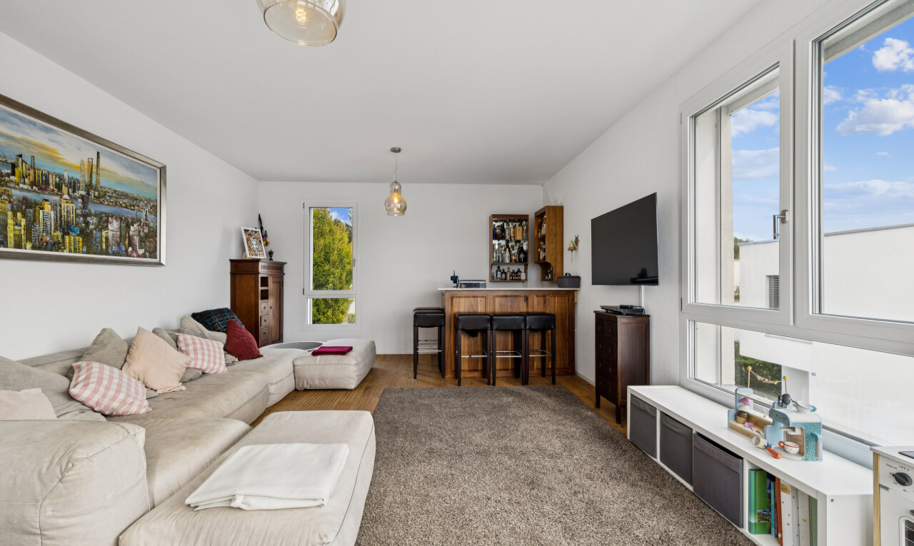 wohnzimmer mit pendelleuchte, natürliches licht, fernseher, und drywall