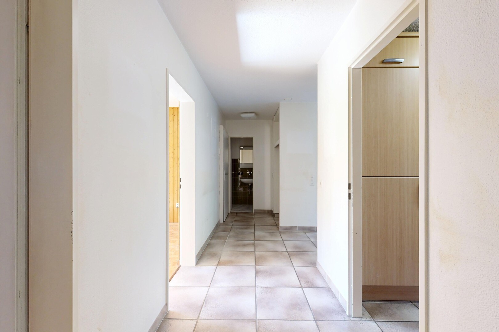 couloir avec inside property, light floor, tile floor, sol en carrelage, et drywall