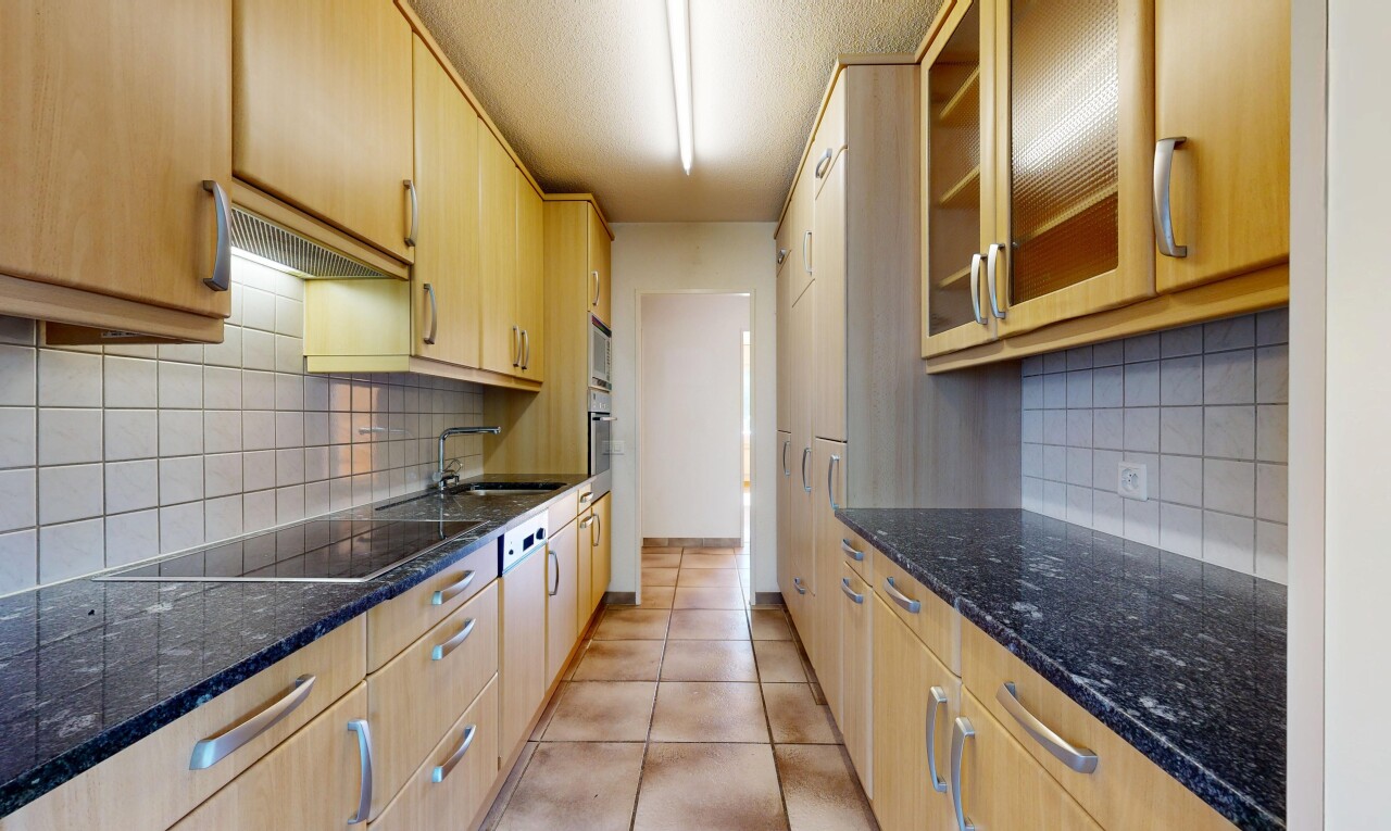cuisine avec glass insert cabinets, armoires avec insert en verre, dark countertops, light brown cabinets, et armoires marron clair
