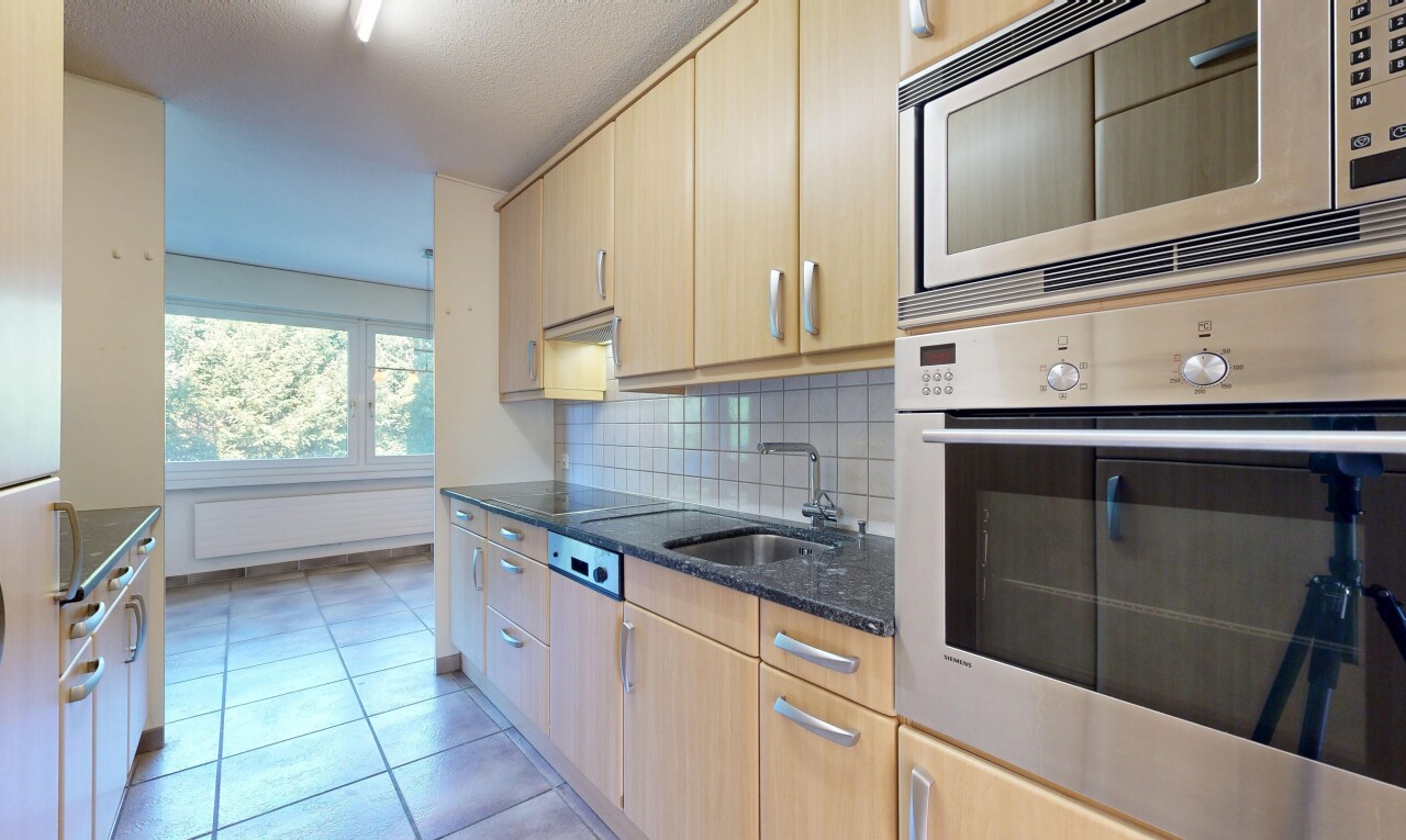 cuisine avec four, dark countertops, light brown cabinets, armoires marron clair, et backsplash