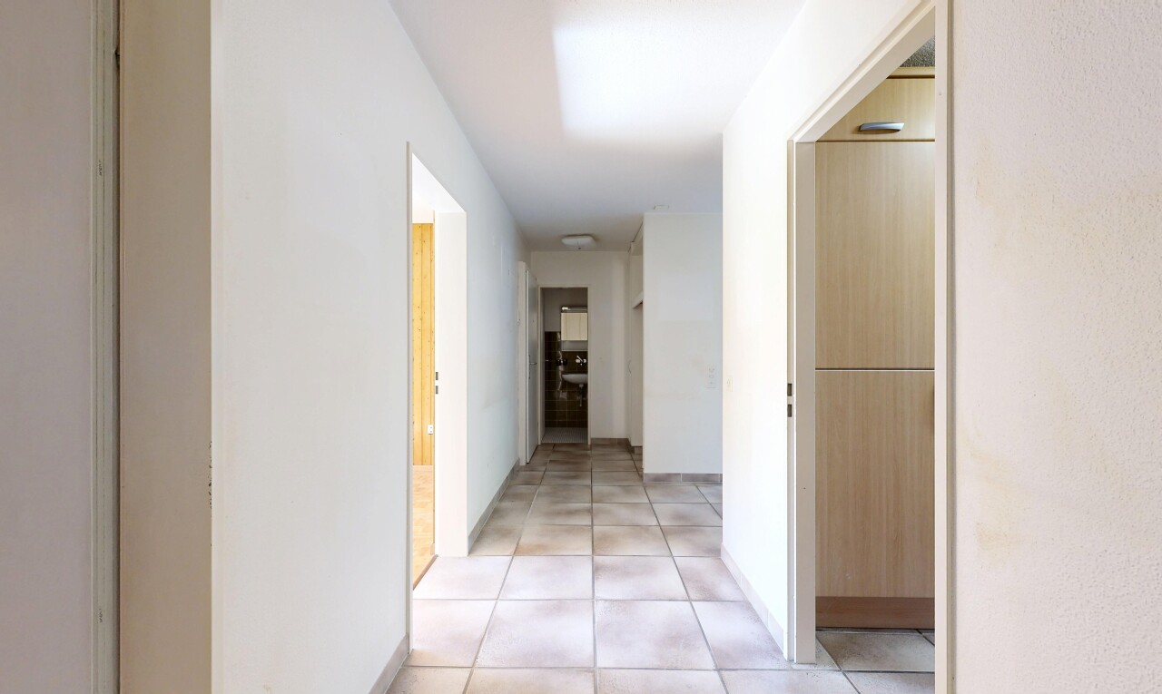 couloir avec inside property, light floor, tile floor, sol en carrelage, et drywall