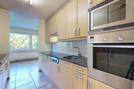 cuisine avec four, dark countertops, light brown cabinets, armoires marron clair, et backsplash
