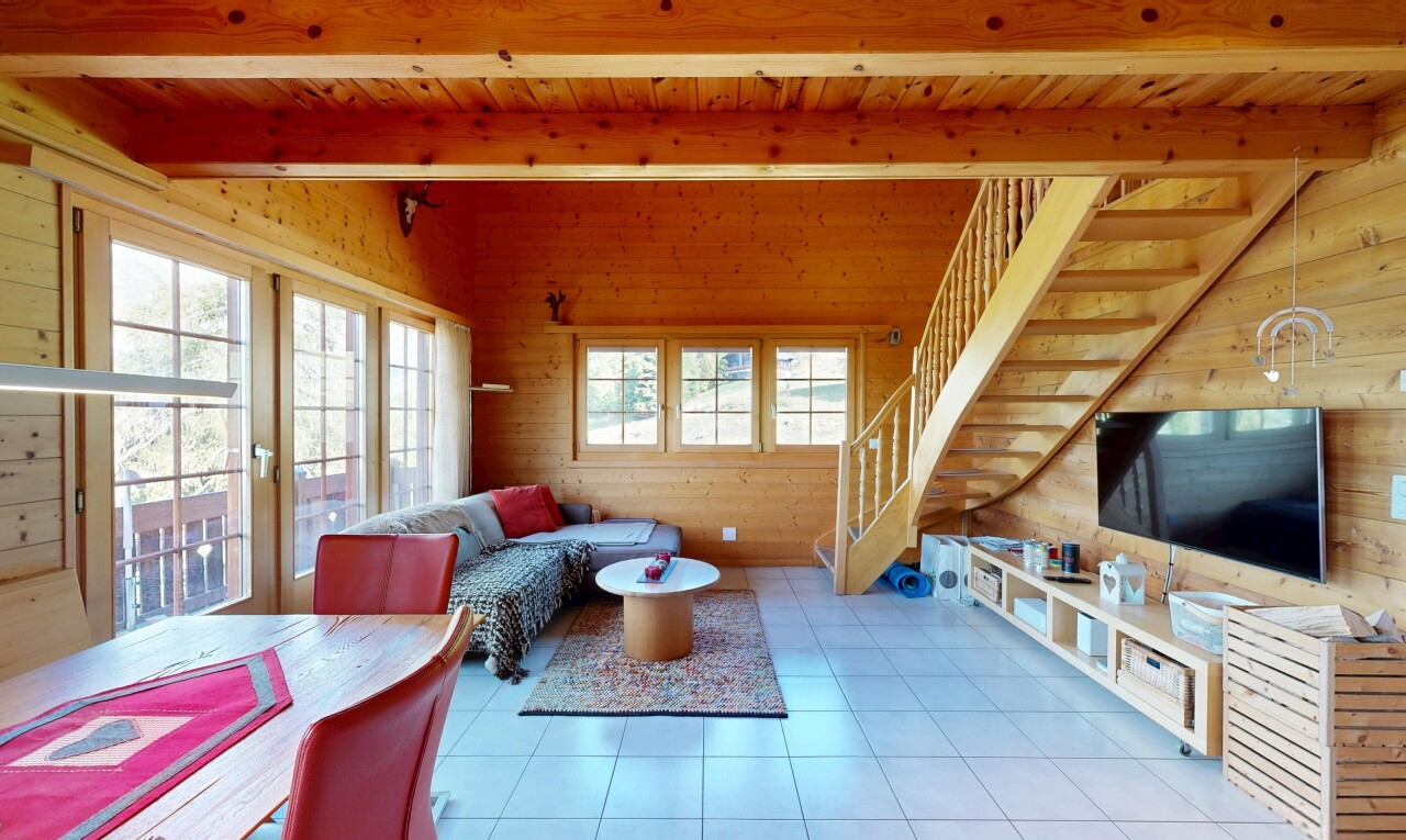 salon / salle à manger avec escaliers, télévision, plafond à poutres, beamed ceiling, et mur en bois
