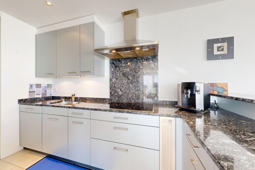 cuisine avec dark countertops, hotte, plans de travail en pierre, stone countertops, et cloison sèche