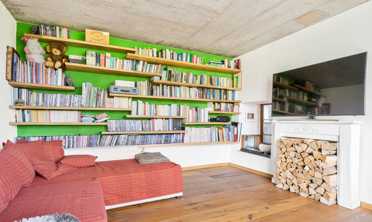 salon avec télévision, wood finish floor, sol en finition bois, inside property, et concrete ceiling