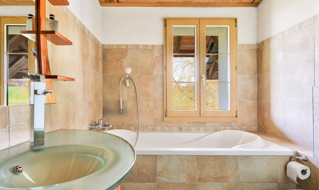 bathroom featuring tile walls, tiled tub, and vanity