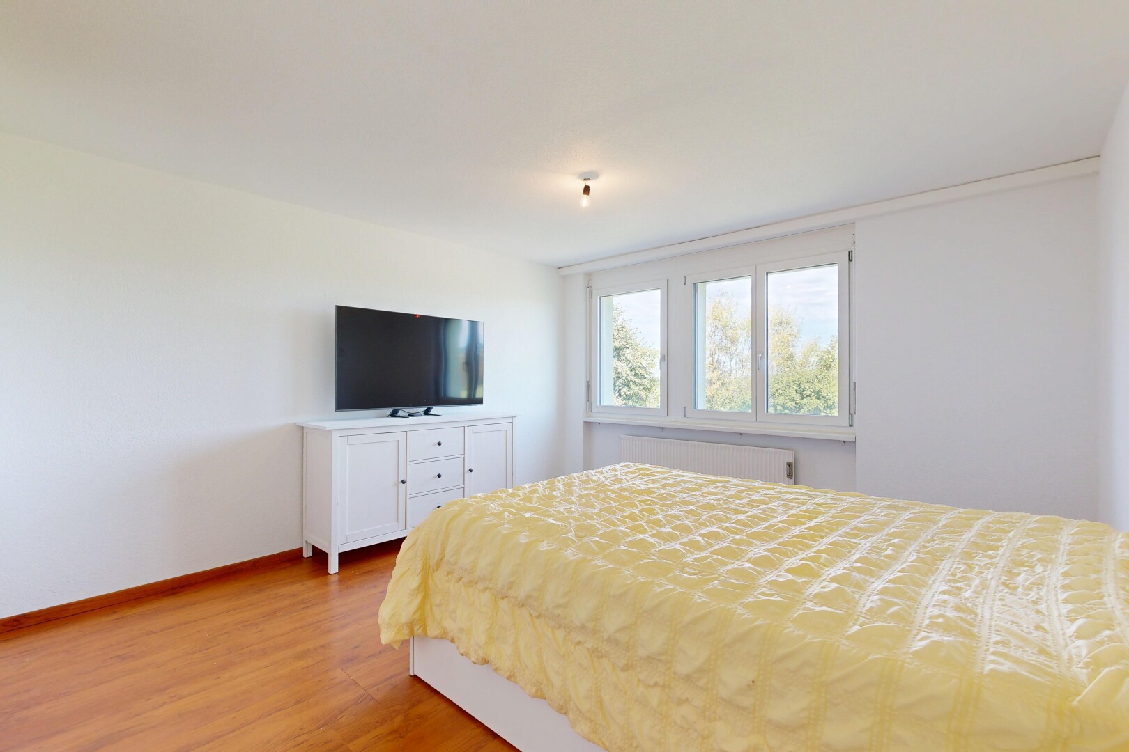 chambre avec télévision, cloison sèche, drywall, sol en finition bois, et wood finish floor