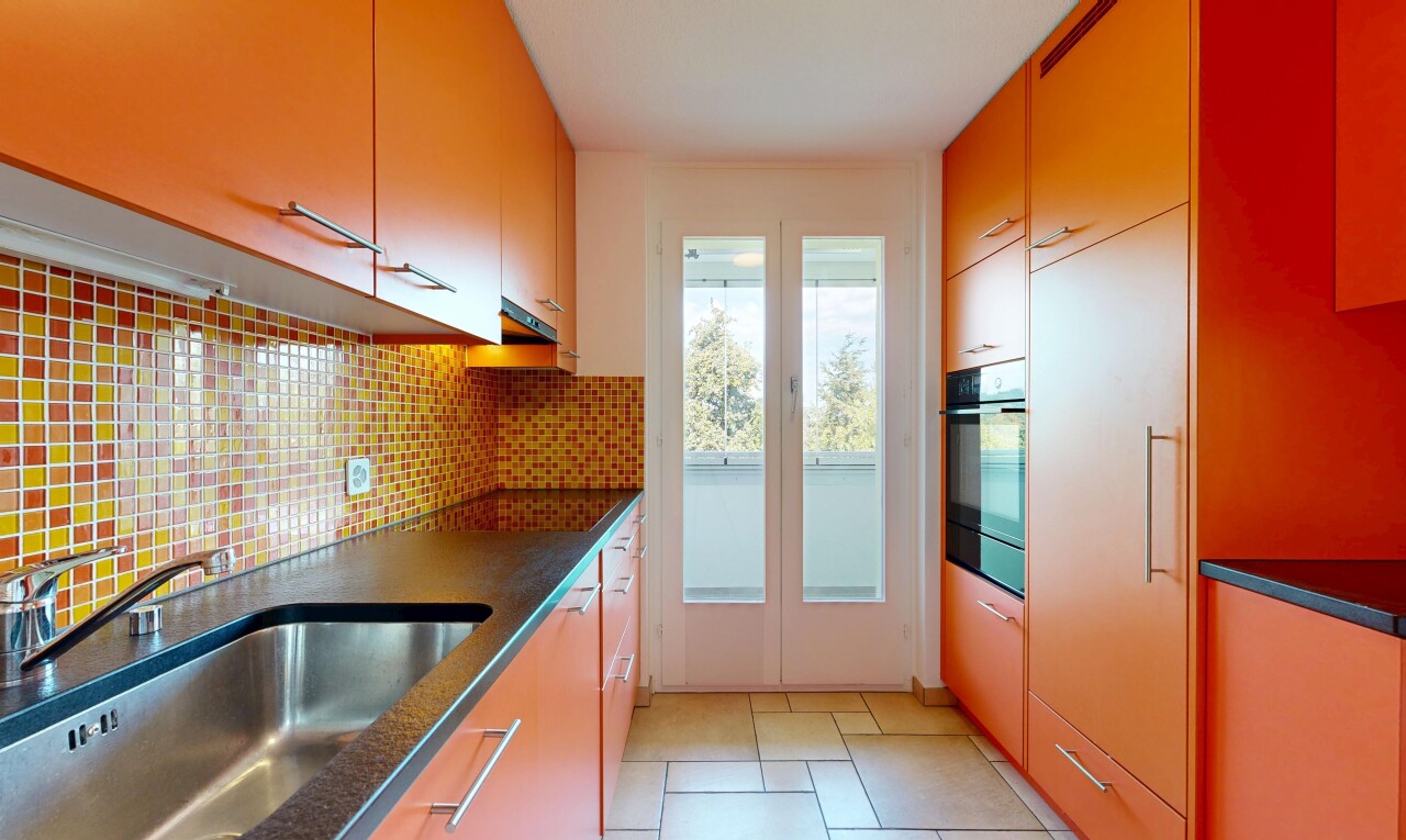 cuisine avec dark countertops, évier, light floor, backsplash, et dosseret