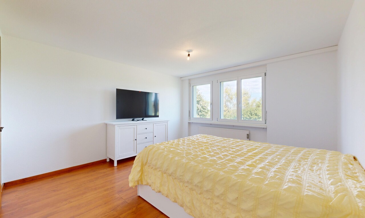 chambre avec télévision, cloison sèche, drywall, sol en finition bois, et wood finish floor