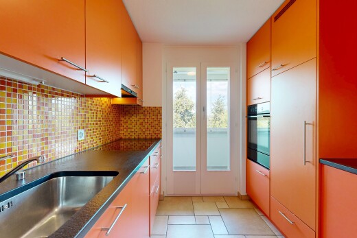 cuisine avec dark countertops, évier, light floor, backsplash, et dosseret