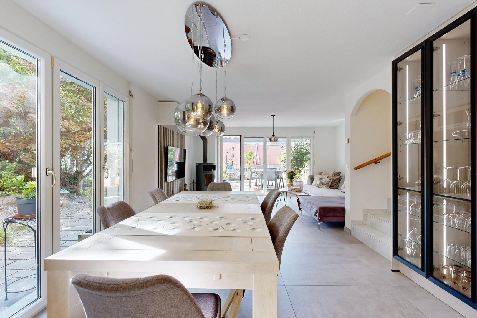 salle à manger avec escaliers, accès à l'extérieur, éclairage suspendu, télévision, et light floor