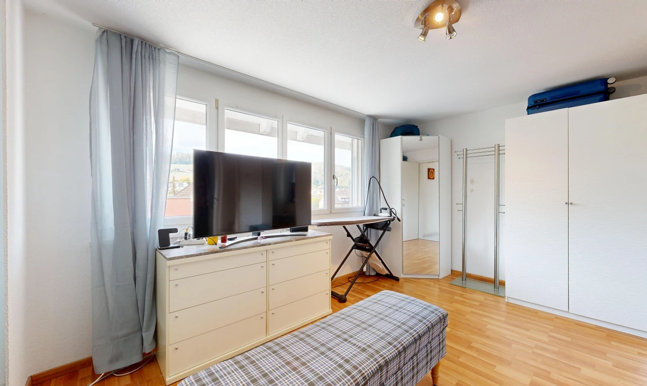 chambre avec télévision, cloison sèche, drywall, sol en finition bois, et wood finish floor