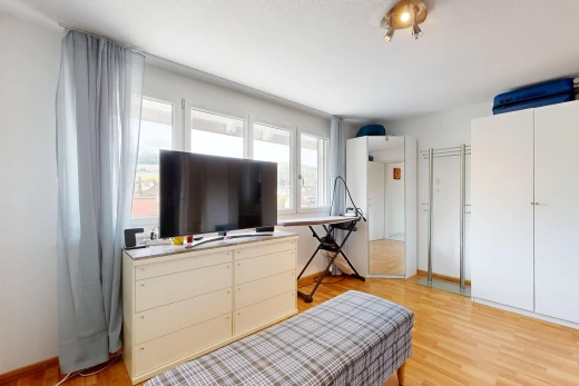 chambre avec télévision, cloison sèche, drywall, sol en finition bois, et wood finish floor