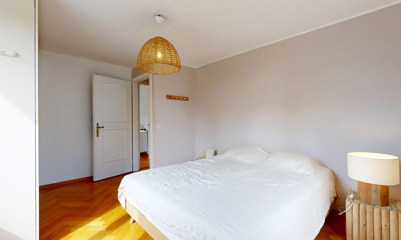 chambre avec éclairage suspendu, wood finish floor, sol en finition bois, drywall, et cloison sèche