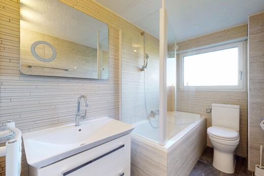 salle de bains avec mur en carrelage, tile wall, miroir, toilette, et lavabo (ou coiffeuse selon le contexte)