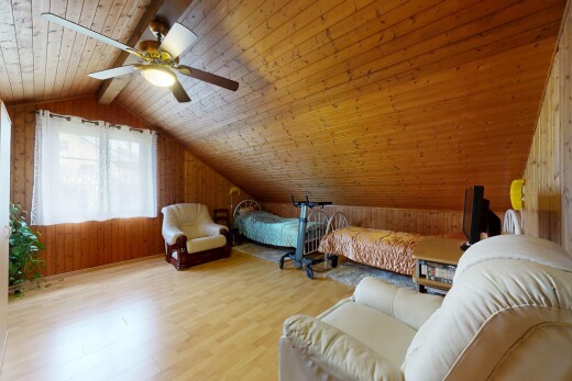 salon avec pièce supplémentaire, plafond voûté, vaulted ceiling, mur en bois, et wood wall