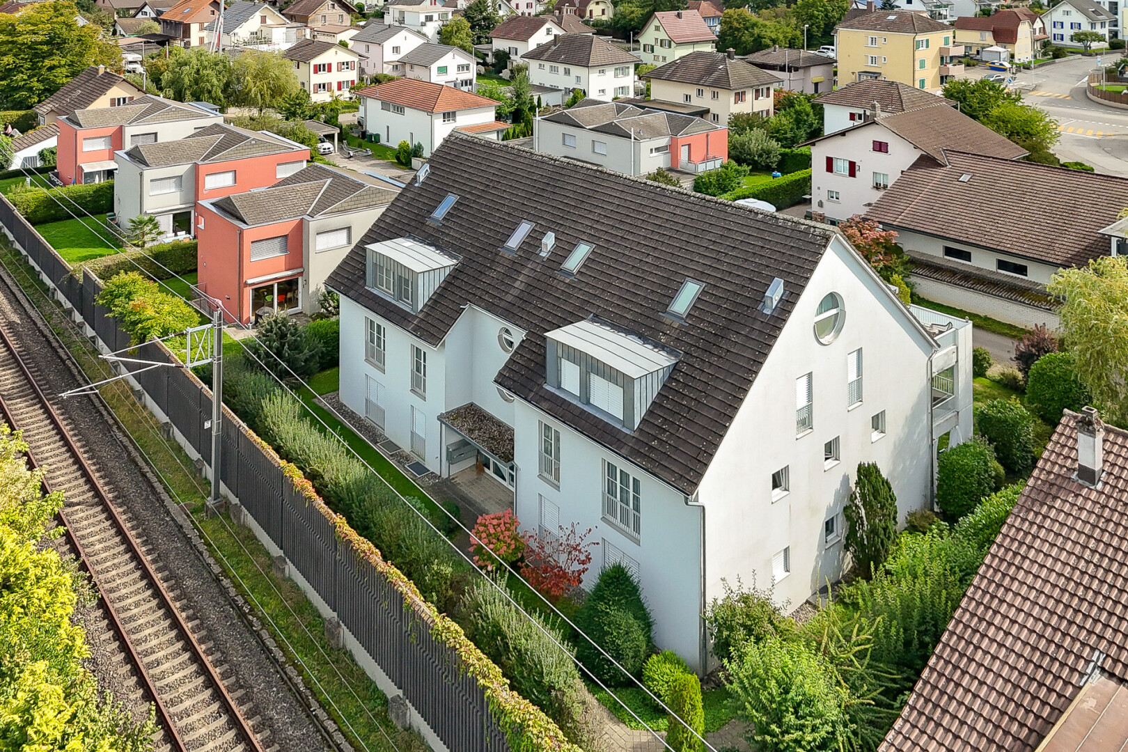 façade avec clôture, drone view, power lines view, bardage en stuc, et toit mansardé