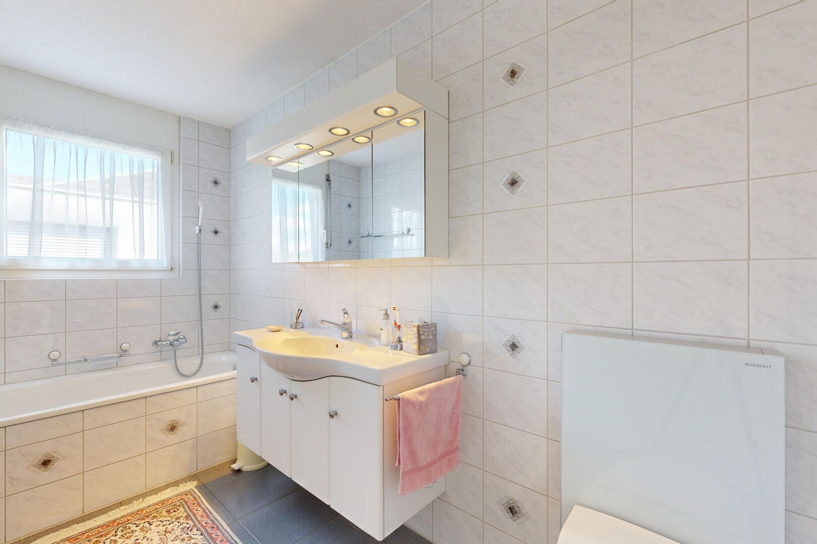 salle de bains avec mur en carrelage, tile wall, lavabo (ou coiffeuse selon le contexte), salle de bain complète, et miroir