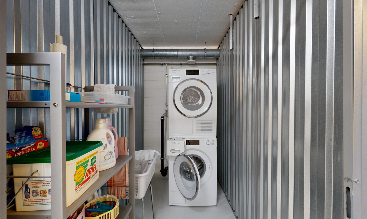 buanderie avec buanderie, inside community, concrete floor, lave-linge et sèche-linge superposés, et mur en métal
