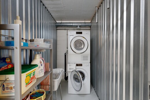 buanderie avec buanderie, inside community, concrete floor, lave-linge et sèche-linge superposés, et mur en métal
