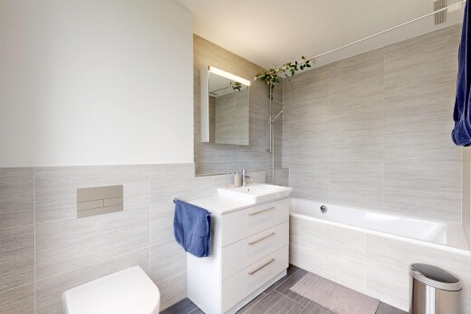 salle de bains avec tile wall, mur en carrelage, salle de bain complète, lavabo (ou coiffeuse selon le contexte), et miroir