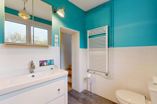 salle de bains avec radiateur, lavabo (ou coiffeuse selon le contexte), miroir, inside property, et lumière naturelle