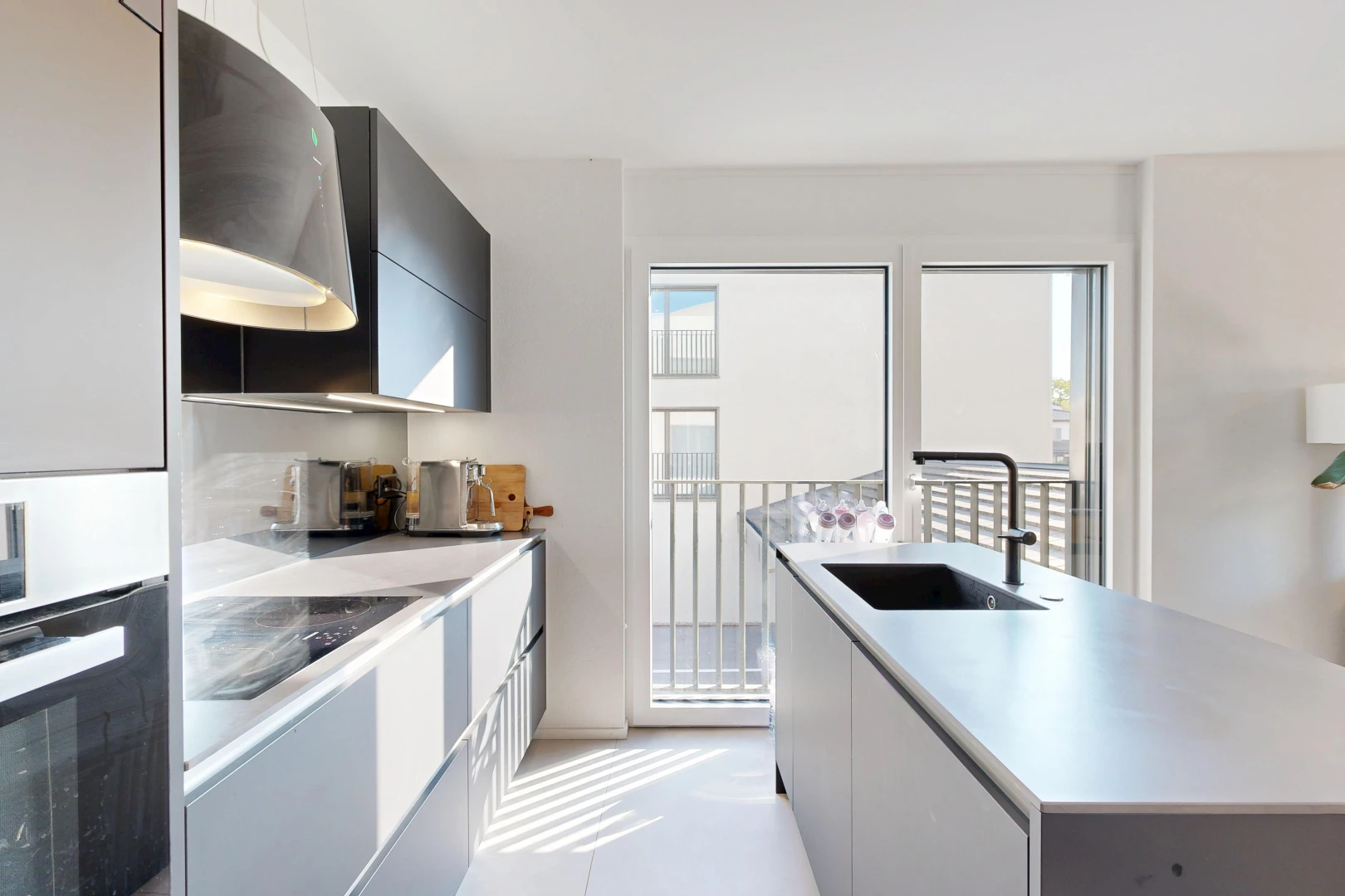 kitchen featuring stainless steel oven, light countertops, a kitchen island with sink, modern cabinets, and two tone cabinets