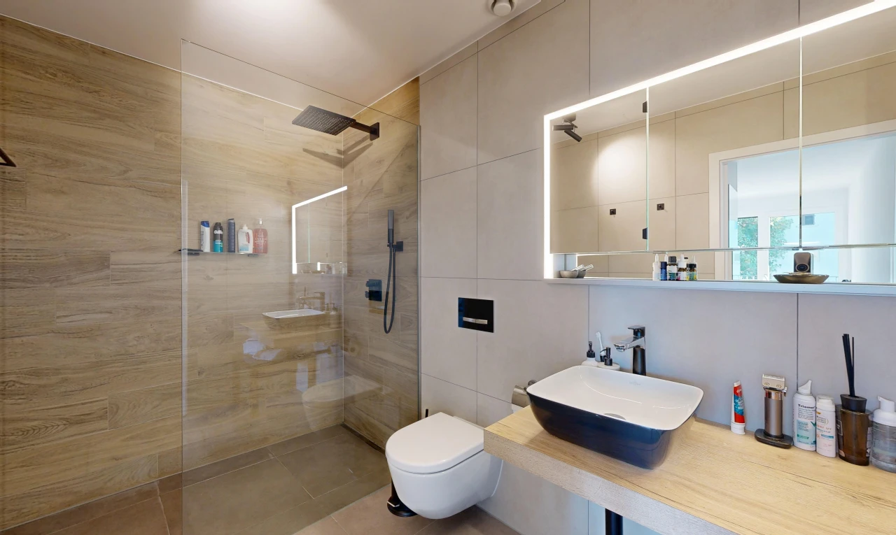 bathroom with a walk in shower, vanity, and tile walls