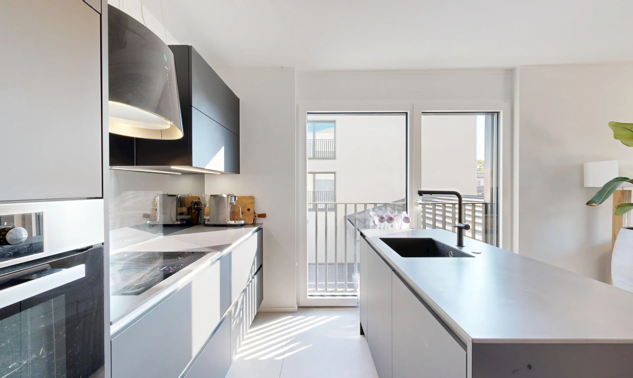 kitchen featuring stainless steel oven, light countertops, a kitchen island with sink, modern cabinets, and two tone cabinets