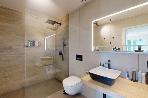 bathroom with a walk in shower, vanity, and tile walls