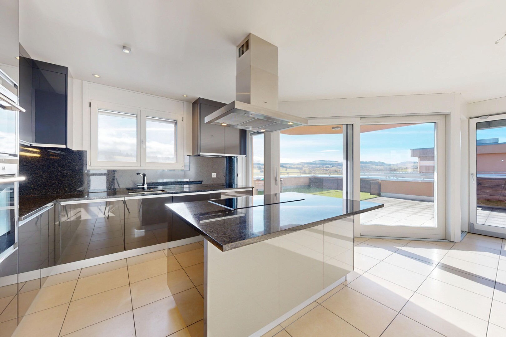 cuisine avec armoires à panneau plat, flat panel cabinets, hotte, dark countertops, et dosseret