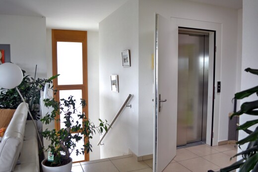 hallway featuring an upstairs landing, light tile patterned floors, and elevator