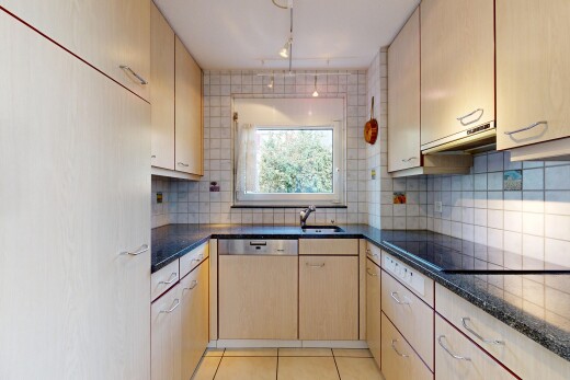 kitchen with backsplash, light tile patterned floors, dishwasher, dark stone countertops, and light wood finish cabinetry