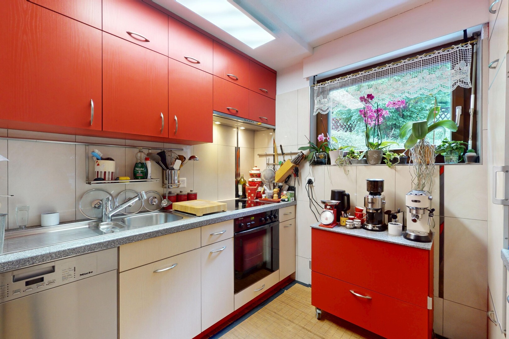 kitchen featuring red cabinets, dishwasher, black oven, and tasteful backsplash