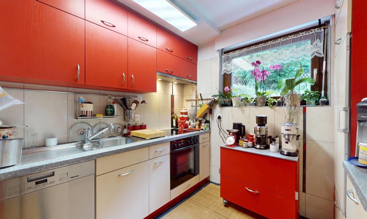 kitchen featuring red cabinets, dishwasher, black oven, and tasteful backsplash