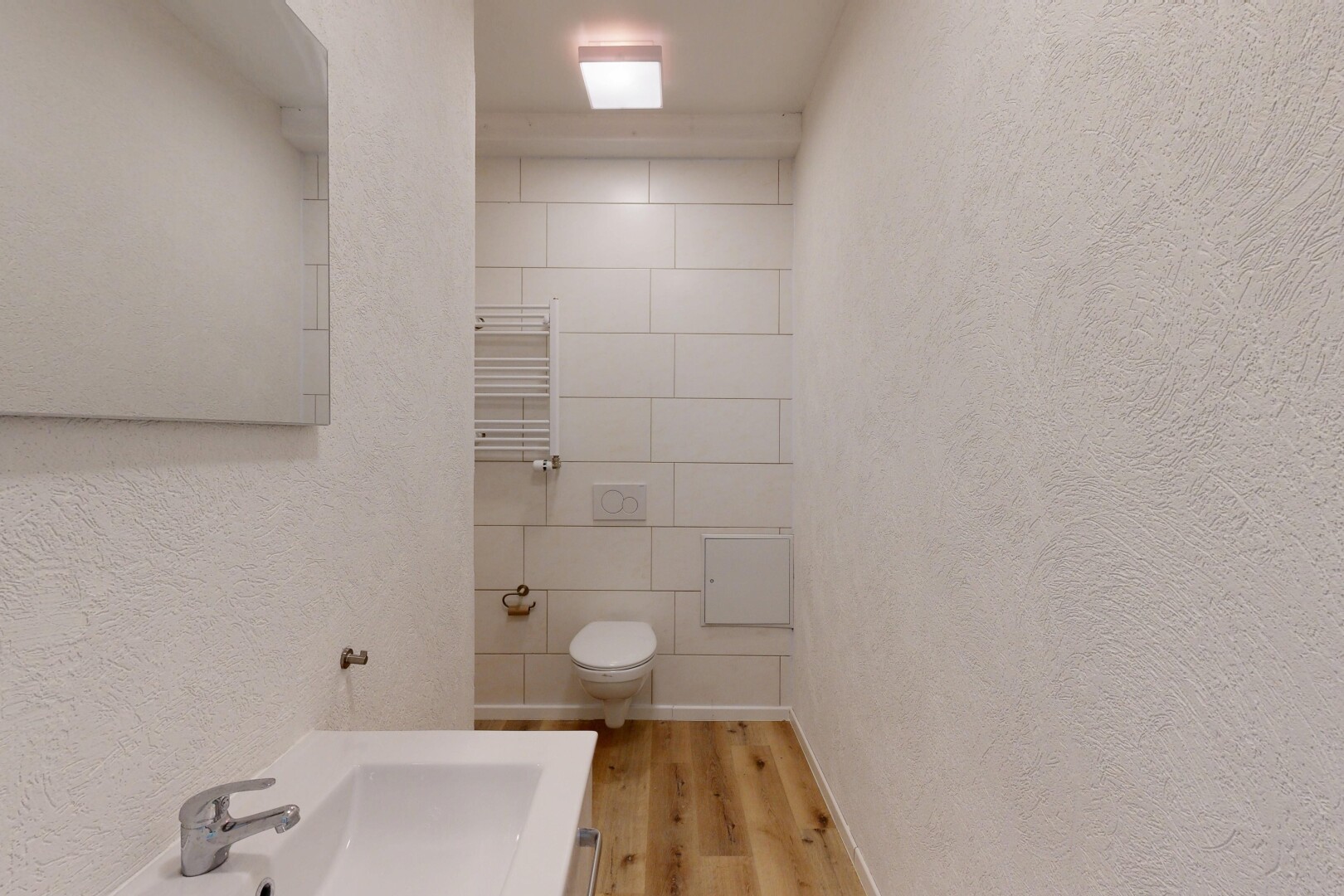 salle de bains avec textured wall, mur texturé, chauffe-serviettes, wood finish floor, et sol en finition bois