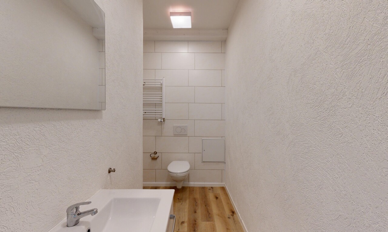 salle de bains avec textured wall, mur texturé, chauffe-serviettes, wood finish floor, et sol en finition bois