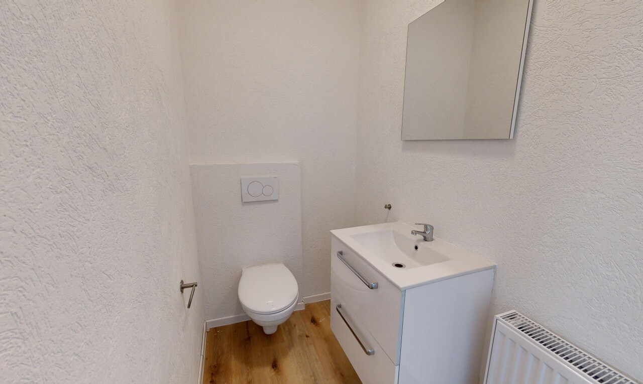 salle de bains avec textured wall, mur texturé, toilette, inside property, et wood finish floor