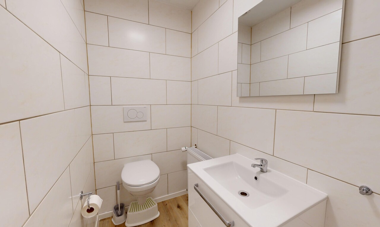 salle de bains avec toilette, tile wall, mur en carrelage, lavabo (ou coiffeuse selon le contexte), et inside property