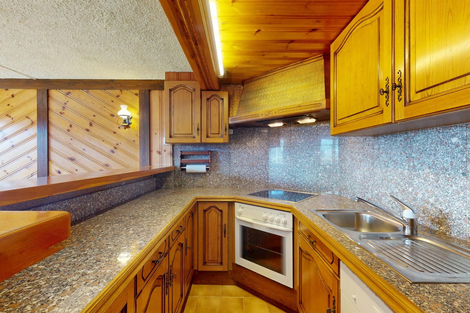 cuisine avec armoires en arc, dosseret, four, plaque de cuisson, et sol en carrelage