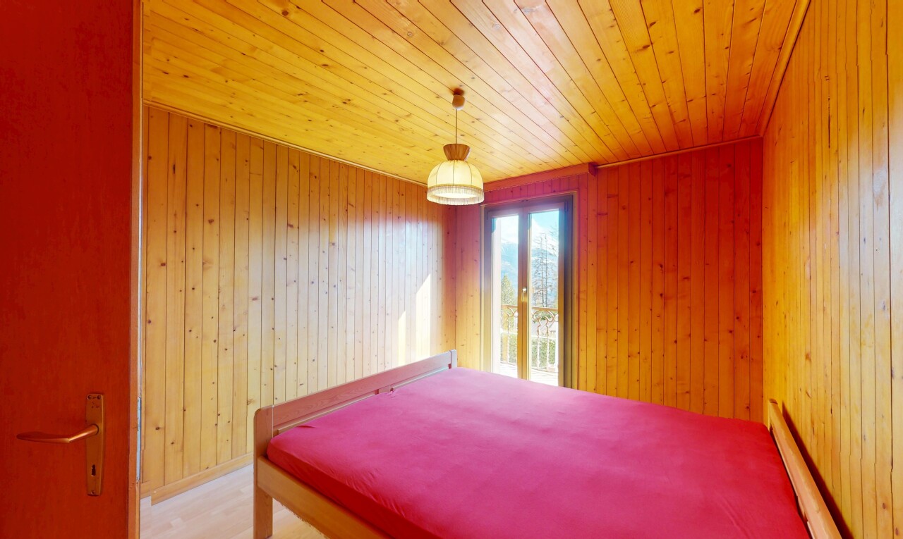 chambre avec mur en bois, plafond en bois, radiateur à plinthe, et lumière naturelle