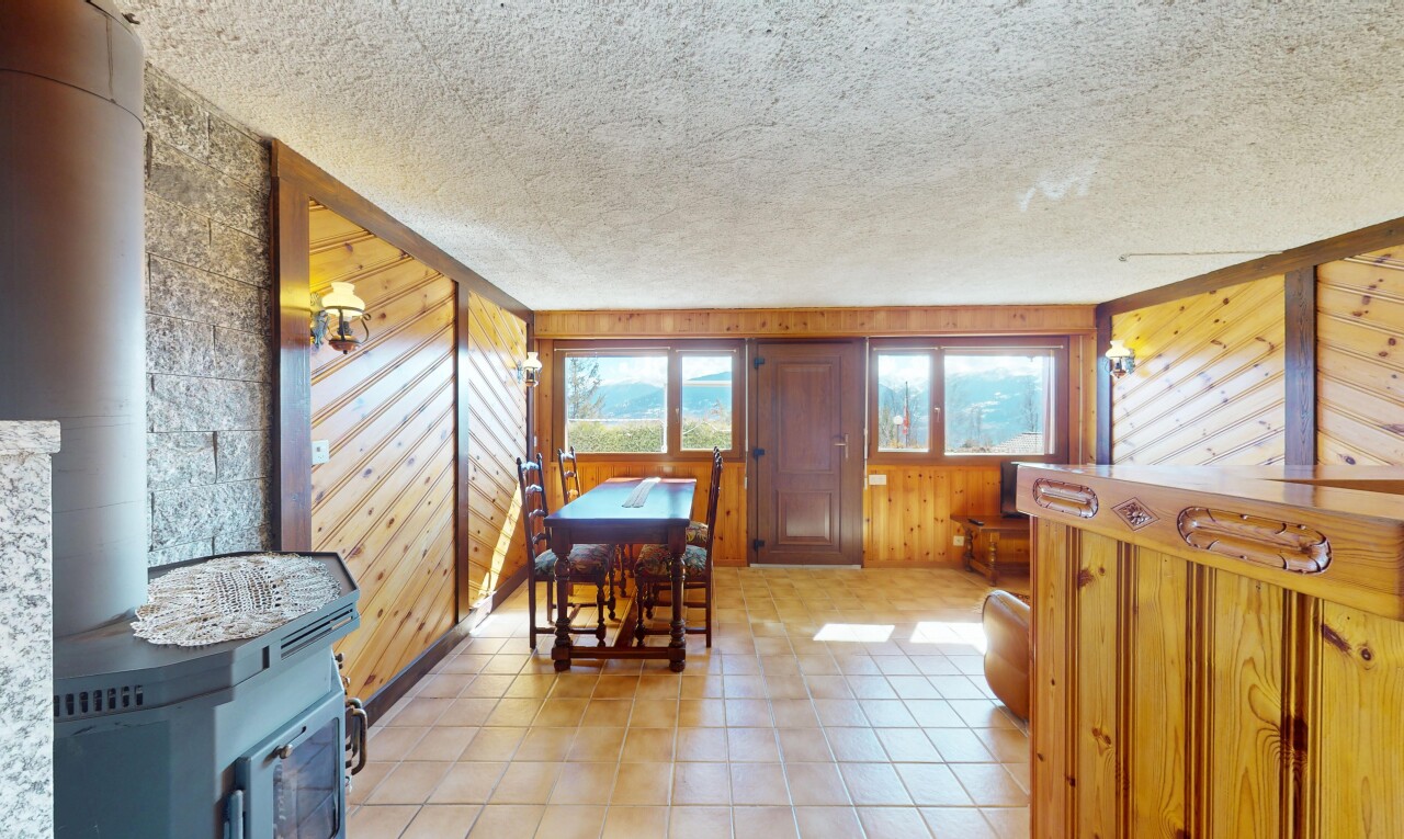 salle à manger avec lumière naturelle, mur en bois, poêle à bois, bar intérieur, et plafond texturé