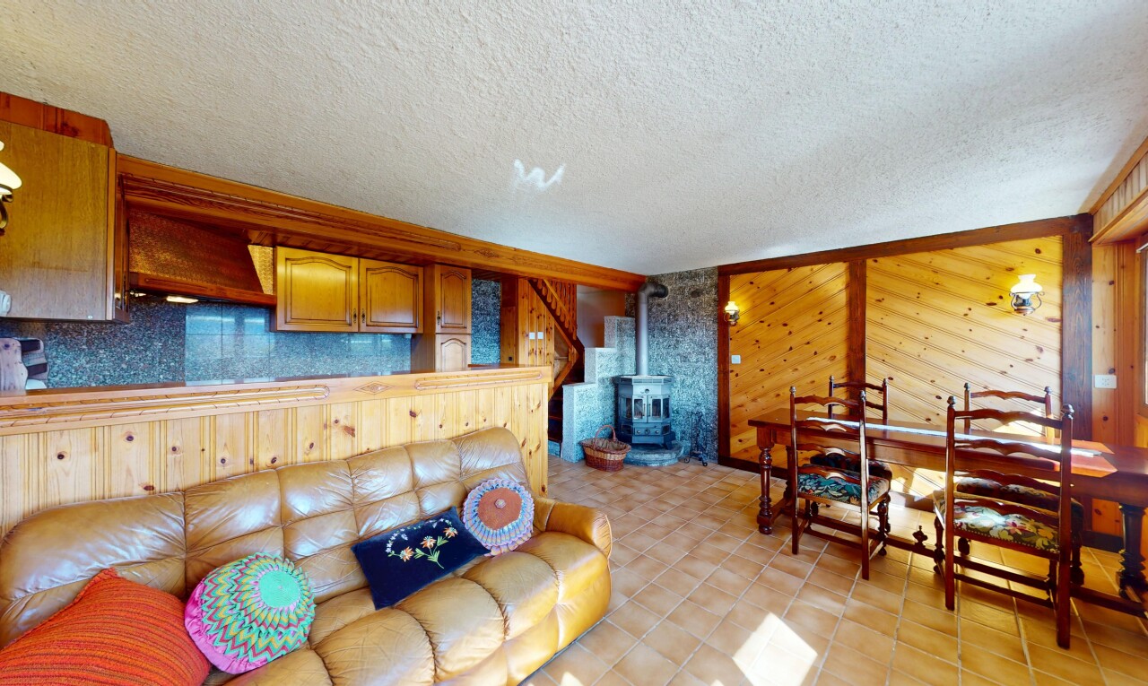 salon / salle à manger avec plafond texturé, poêle à bois, et mur en bois