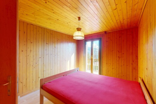 chambre avec mur en bois, plafond en bois, radiateur à plinthe, et lumière naturelle