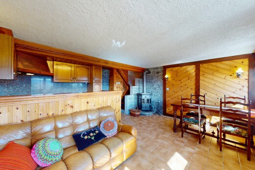 salon / salle à manger avec plafond texturé, poêle à bois, et mur en bois