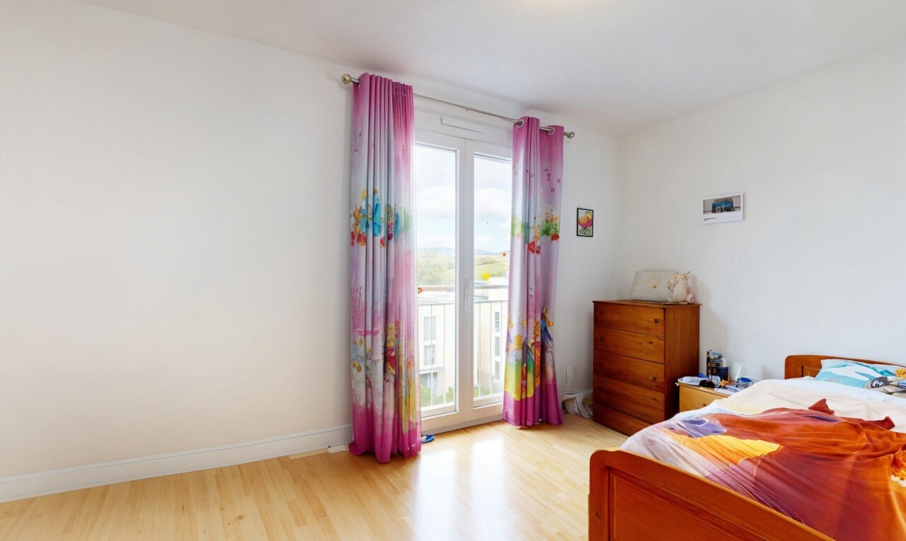 chambre avec wood finish floor, sol en finition bois, drywall, cloison sèche, et natural light