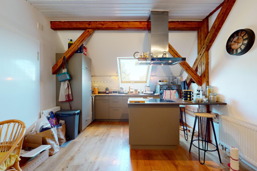 cuisine avec hotte, poutres apparentes, lumière naturelle, plancher de bois, et radiateur