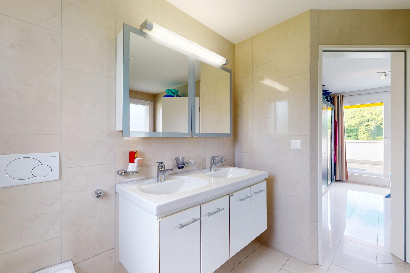 salle de bains avec mur en carrelage, évier, et lumière naturelle
