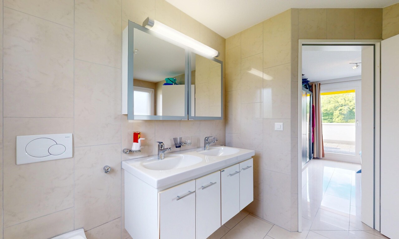 salle de bains avec mur en carrelage, évier, et lumière naturelle