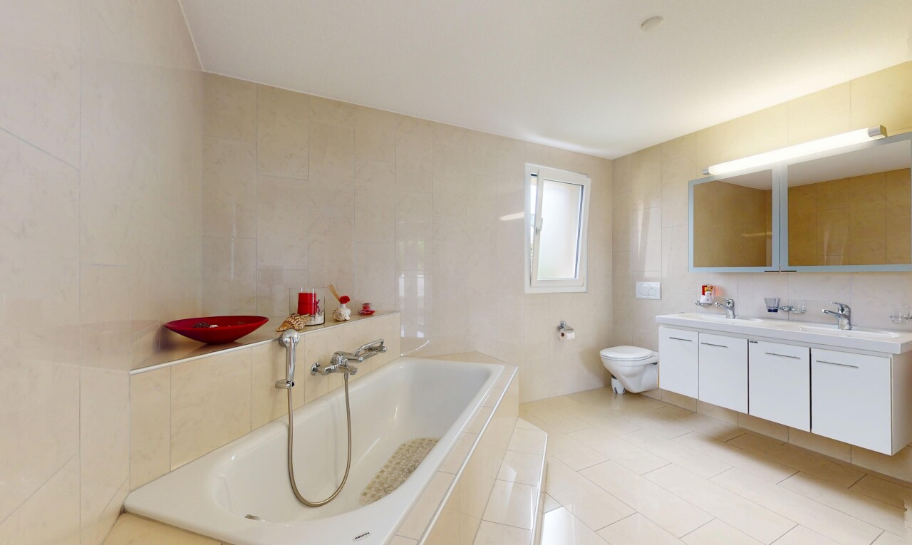salle de bains avec bain, miroir, salle de bain complète, mur en carrelage, et lumière naturelle